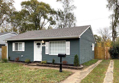 A small house with a white door and a mailbox in front.