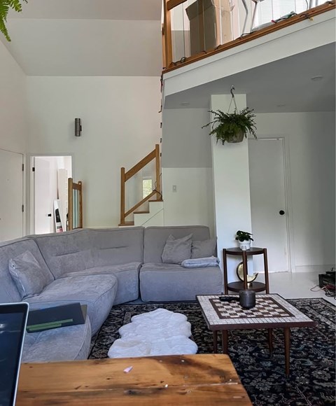 A grey couch sits in a living room with a wooden table in front of it.