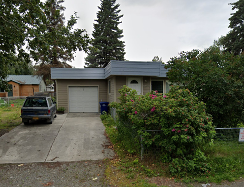 A house with a garage and a car parked in front.