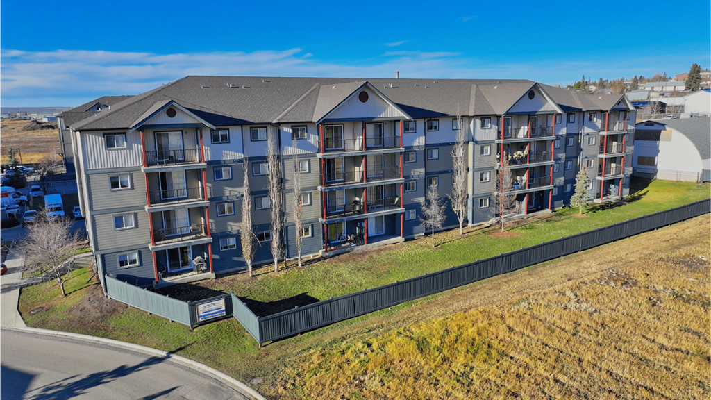 A large apartment complex with multiple balconies and a green fence in front.