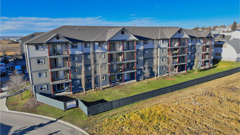 A large apartment complex with multiple balconies and a green fence in front.