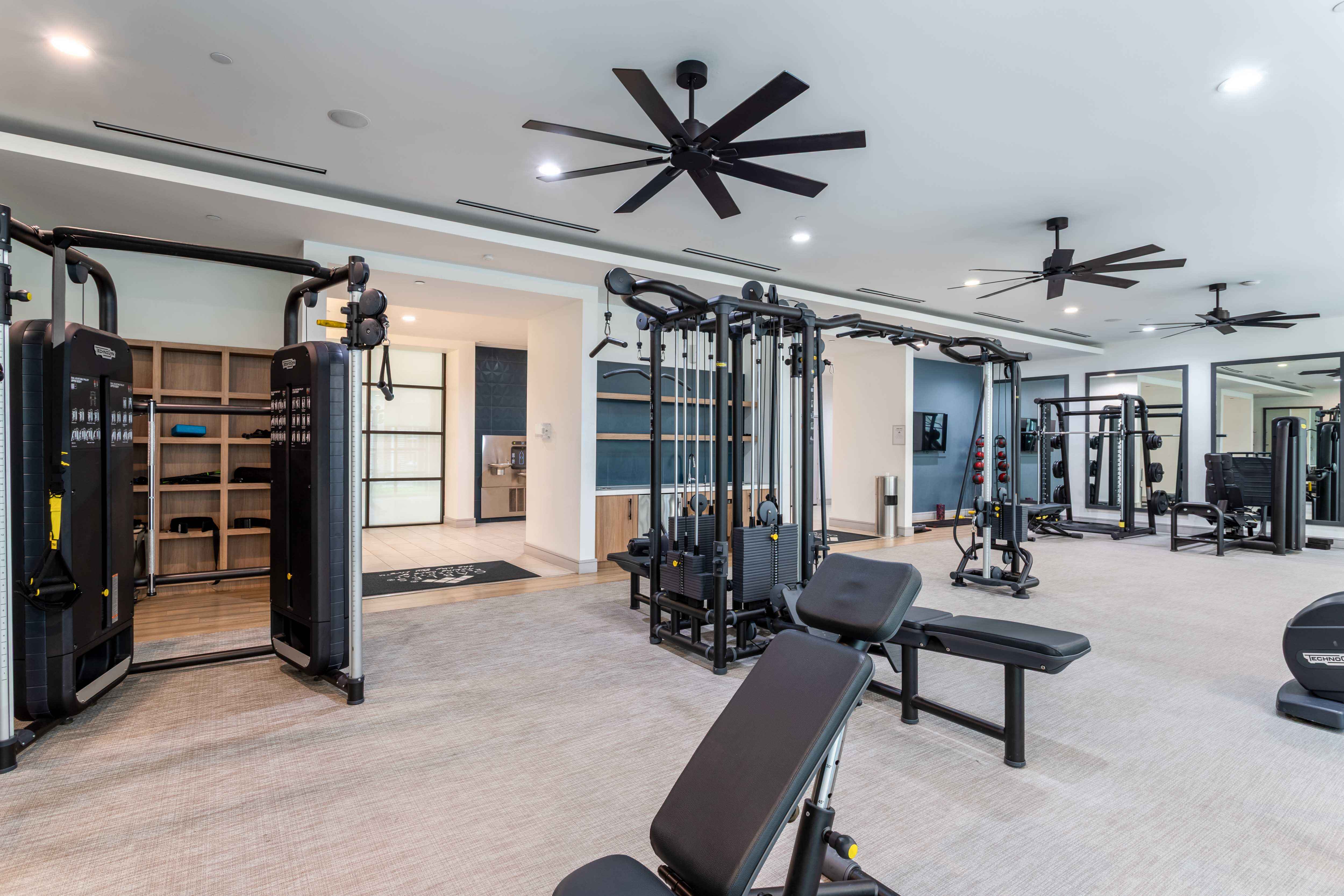 A spacious gym with a variety of equipment and a ceiling fan.