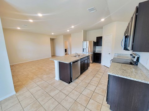 A kitchen with a refrigerator, microwave, and oven.