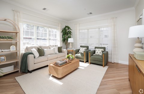 A living room with a white couch, a green armchair, and a wooden coffee table.
