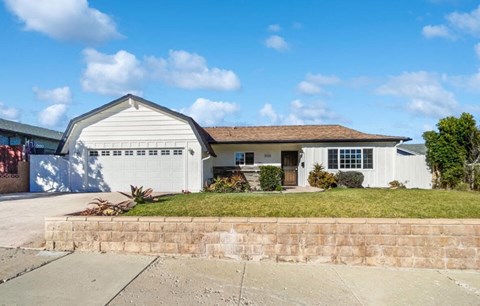 A white house with a brown roof and a garage door.