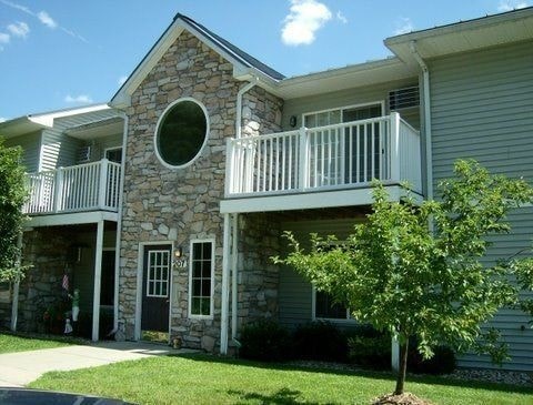 A stone building with a balcony and a tree in front.