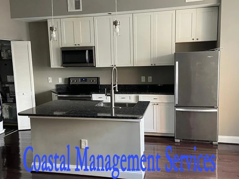 A kitchen with a black countertop and a refrigerator.