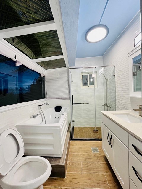 A white toilet is in a modern bathroom with a walk-in shower.