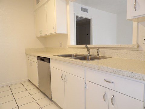 A kitchen with white cabinets and a sink.