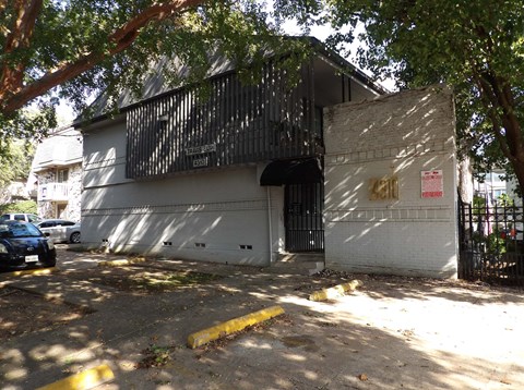 A white building with a black gate and a sign that reads "Banco".