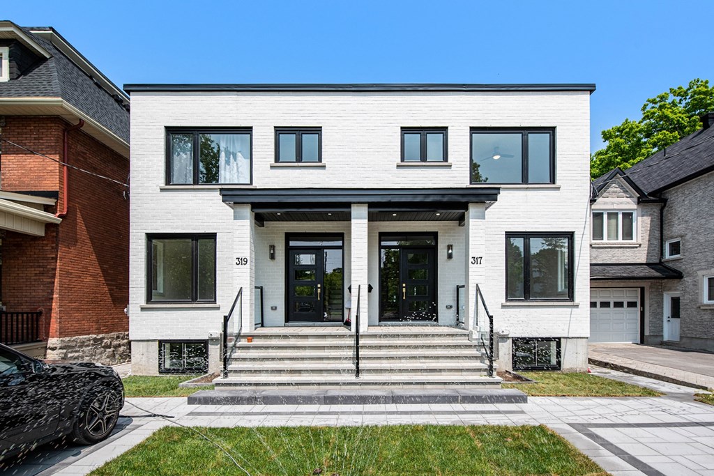 A modern two-story house with a black car parked in front.