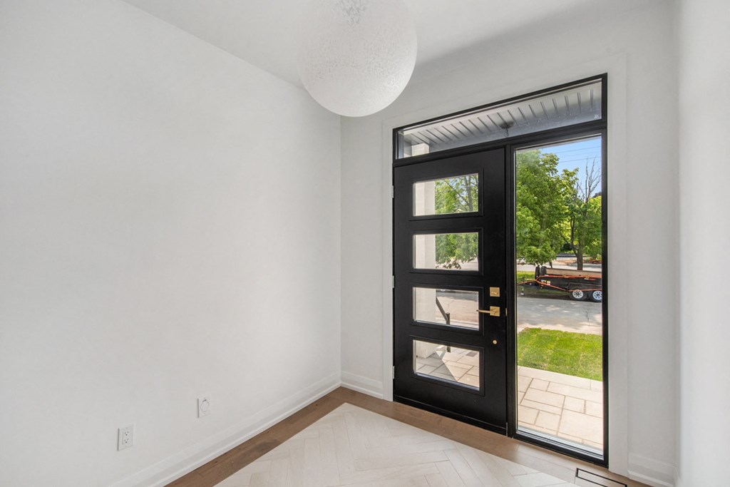 A black door with a glass panel is open to a patio.