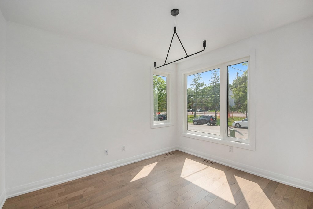 A room with a white wall and a window with a view of a street.