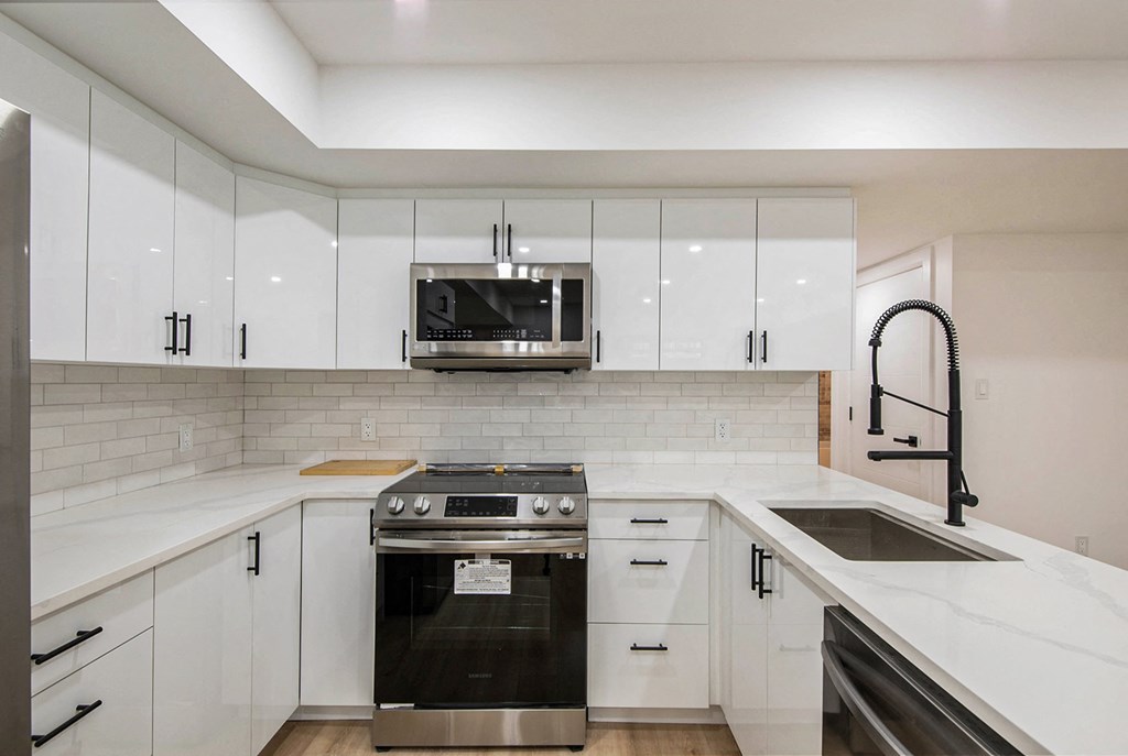 A modern kitchen with white cabinets and a stainless steel oven.