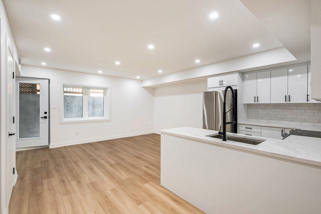 A kitchen with a refrigerator, sink, and cabinets.