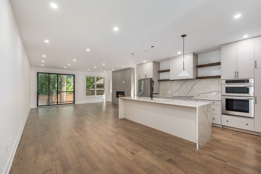 A modern kitchen with wooden floors and white cabinetry.