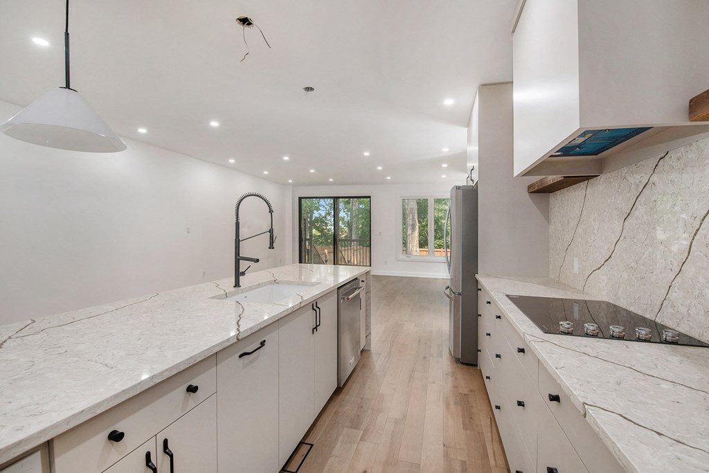 A modern kitchen with white marble countertops and wooden floors.