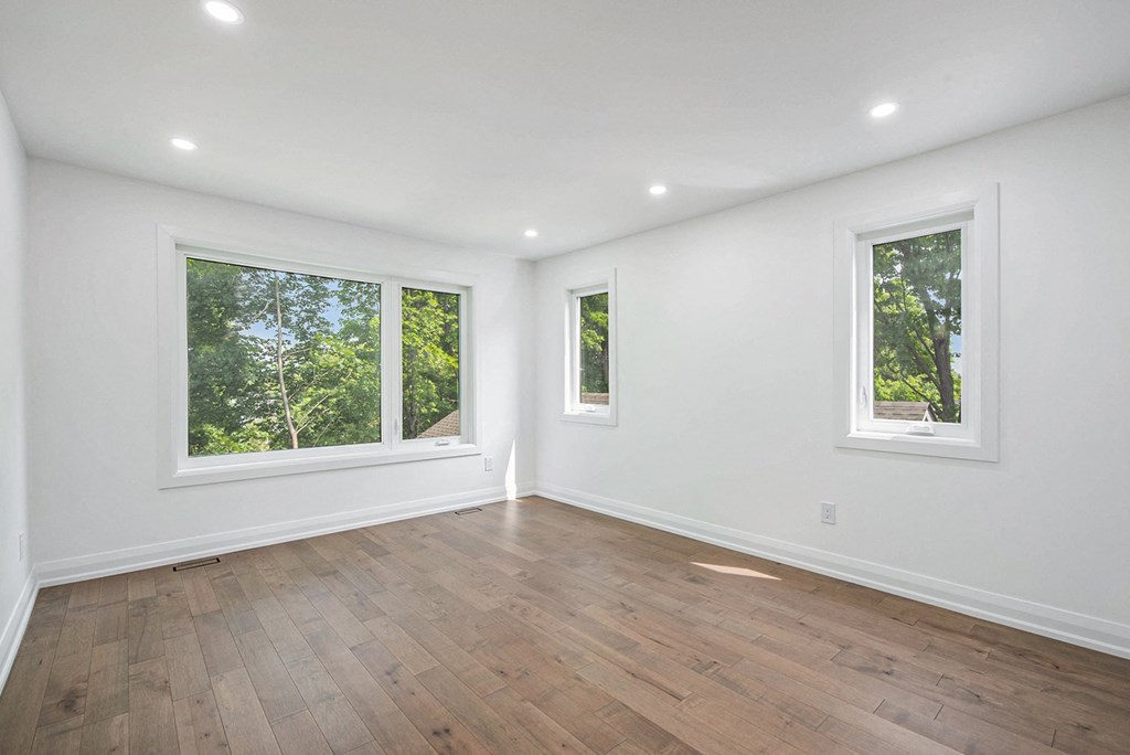 A room with two windows and wooden flooring.