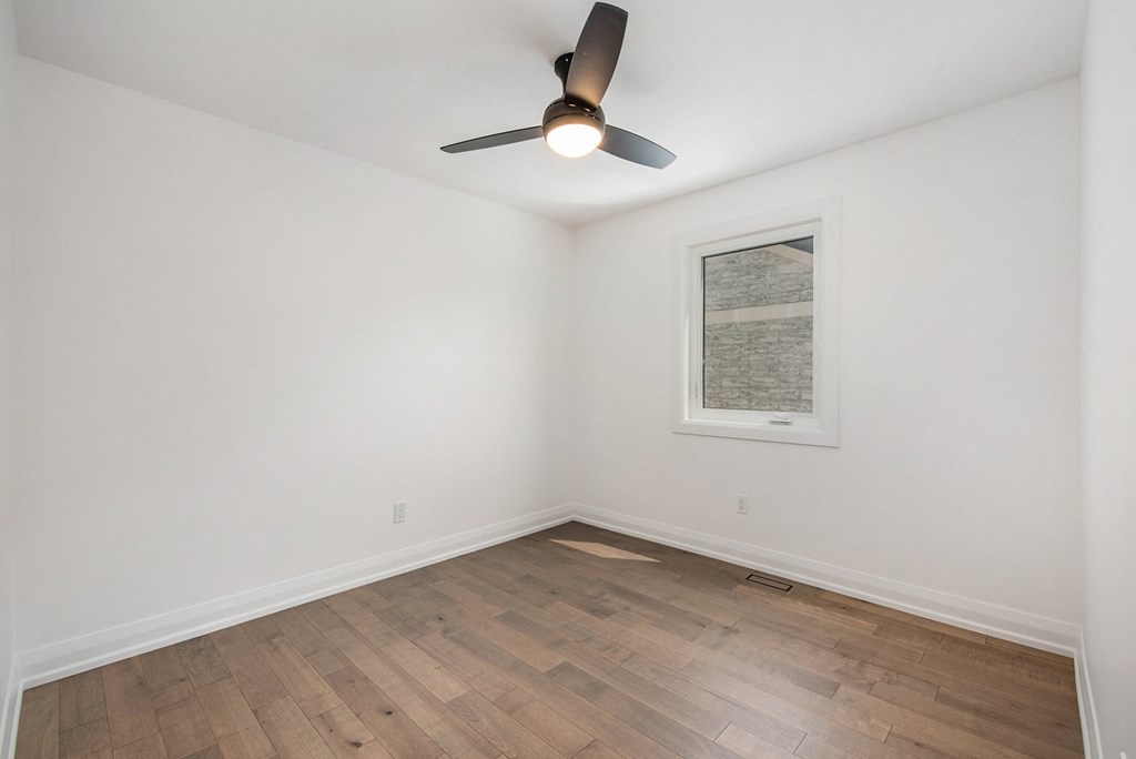 A room with a ceiling fan and a picture on the wall.