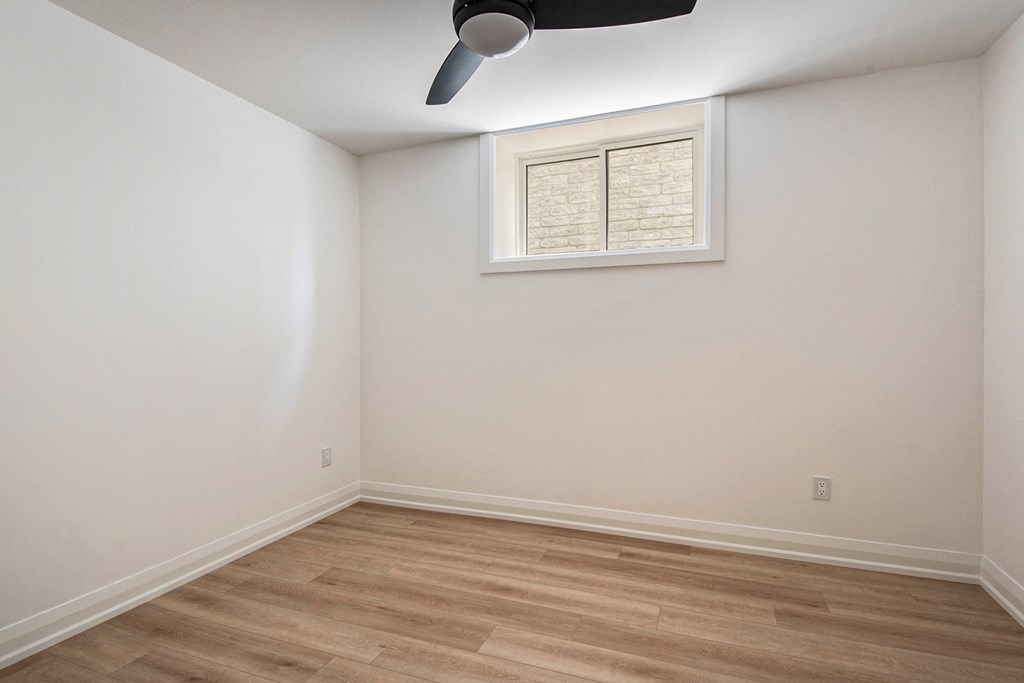 A room with a ceiling fan and a window with blinds.