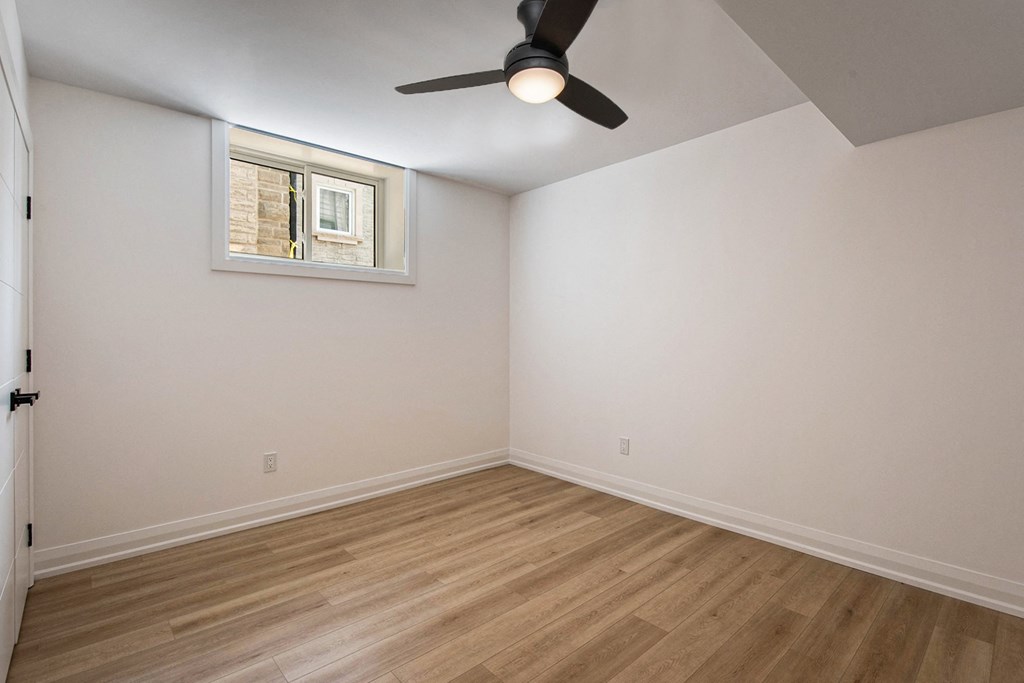 A room with a ceiling fan and a window with blinds.