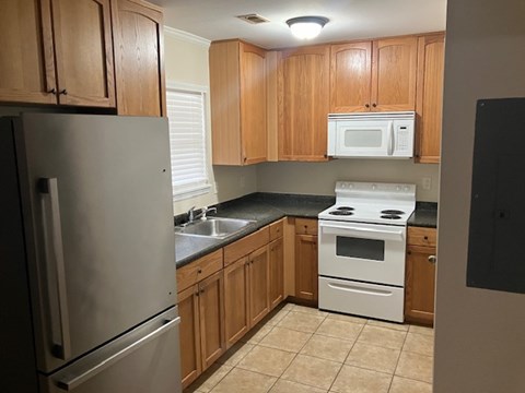 A kitchen with wooden cabinets and a white stove top oven.