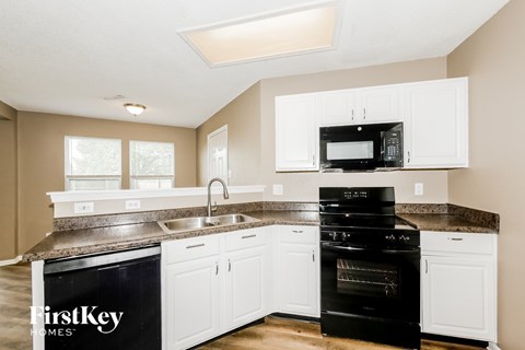A kitchen with a black oven and white cabinets.