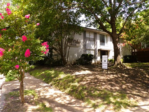 A white sign with black text is in front of a house.