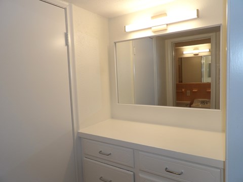 A white bathroom vanity with a mirror and lights above it.
