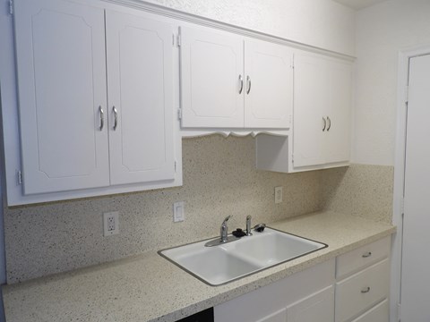 A kitchen with white cabinets and a sink.
