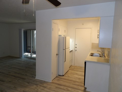 A kitchen area with a sink, refrigerator, and cabinets.