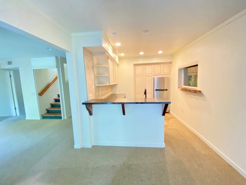 A spacious kitchen with a bar counter and a staircase in the background.