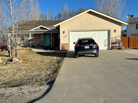 A house with a garage and a car parked in front.