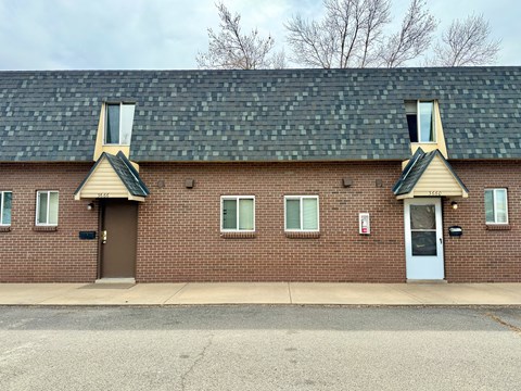 A brick building with a green roof and two white doors.