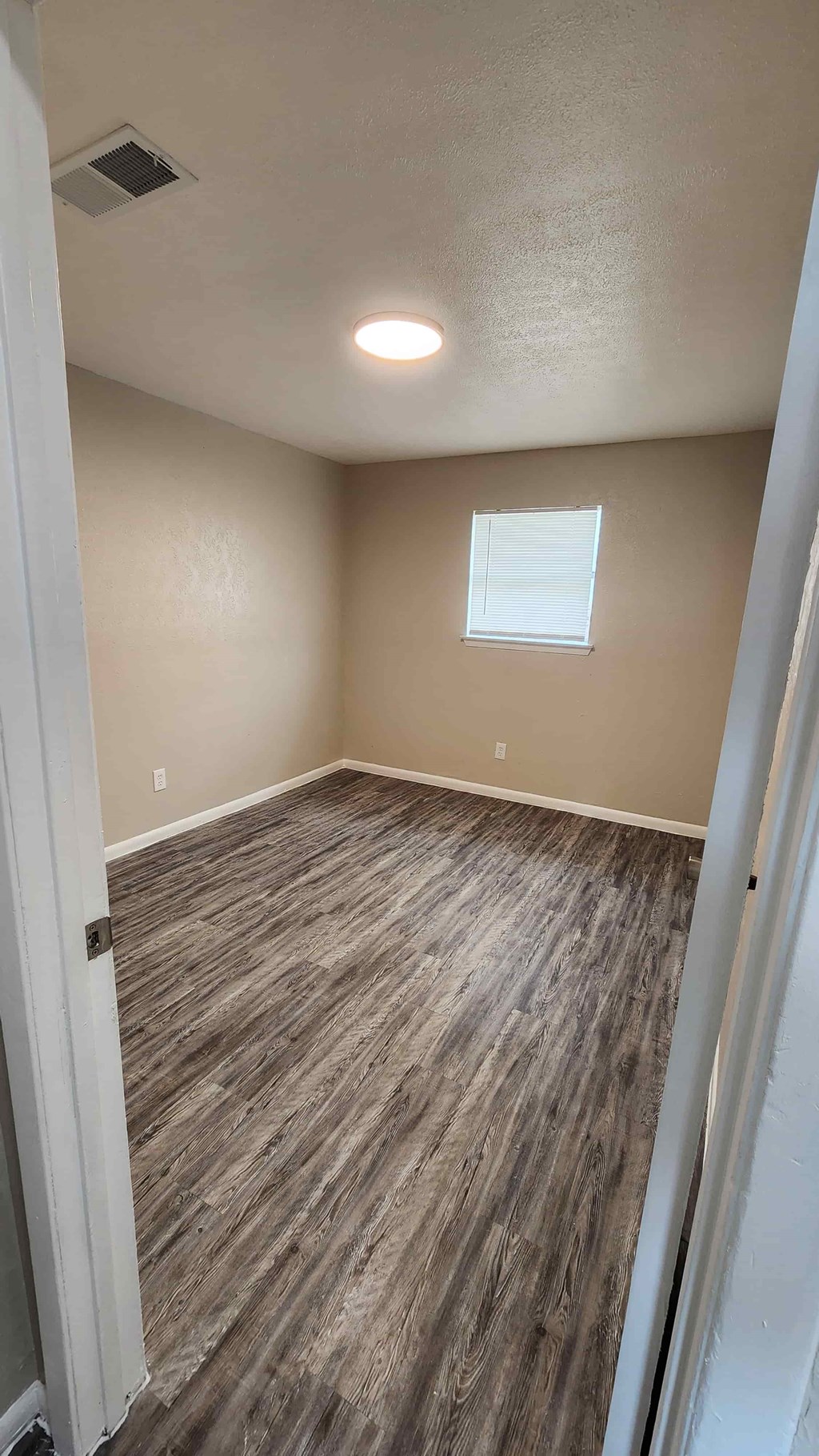 A room with a window and a wooden floor.
