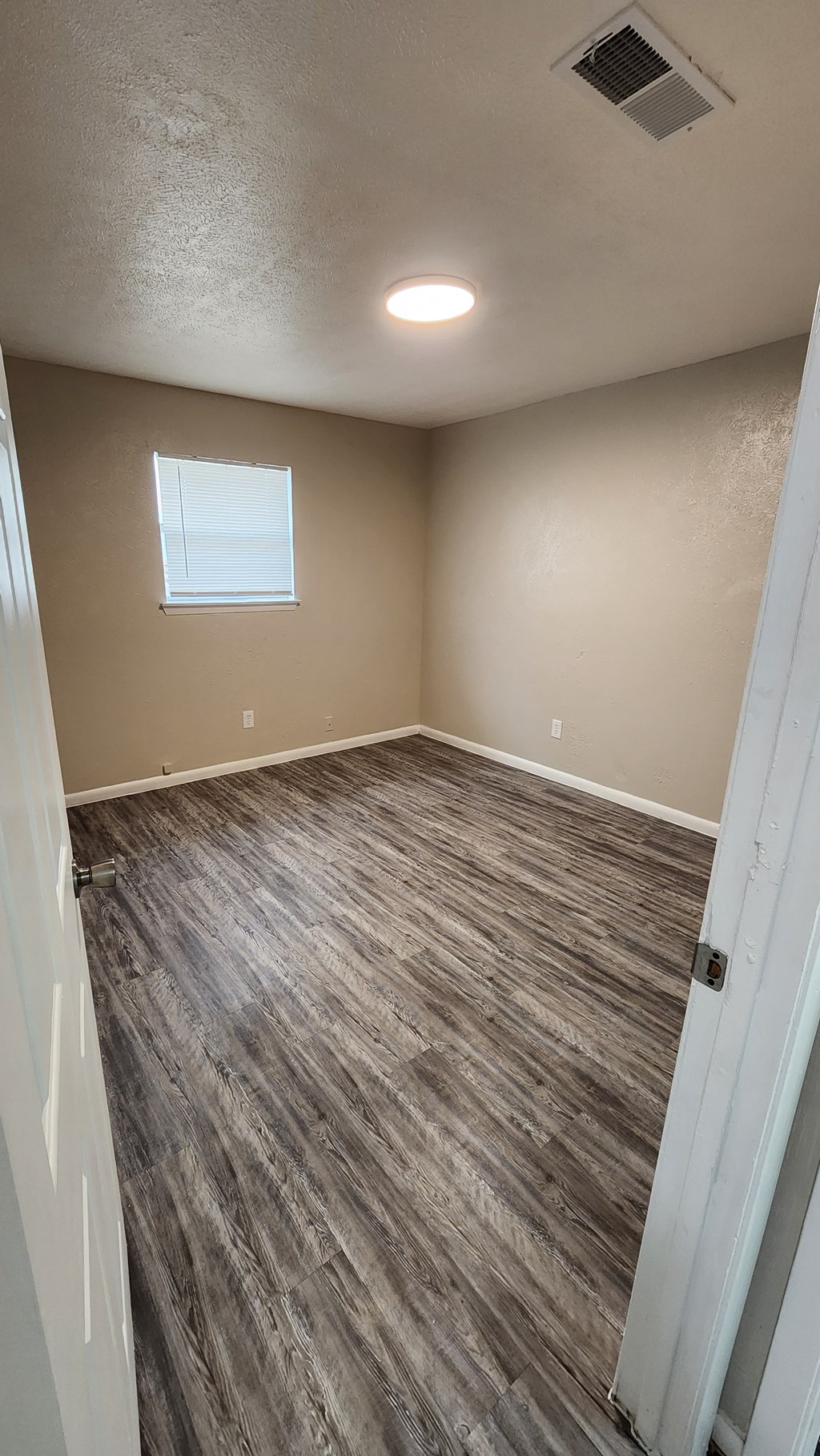 A room with a window and a wooden floor.