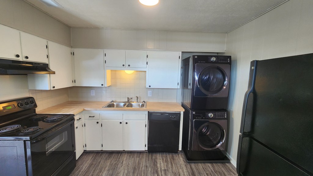 A black and white kitchen with a black fridge and a black washing machine.