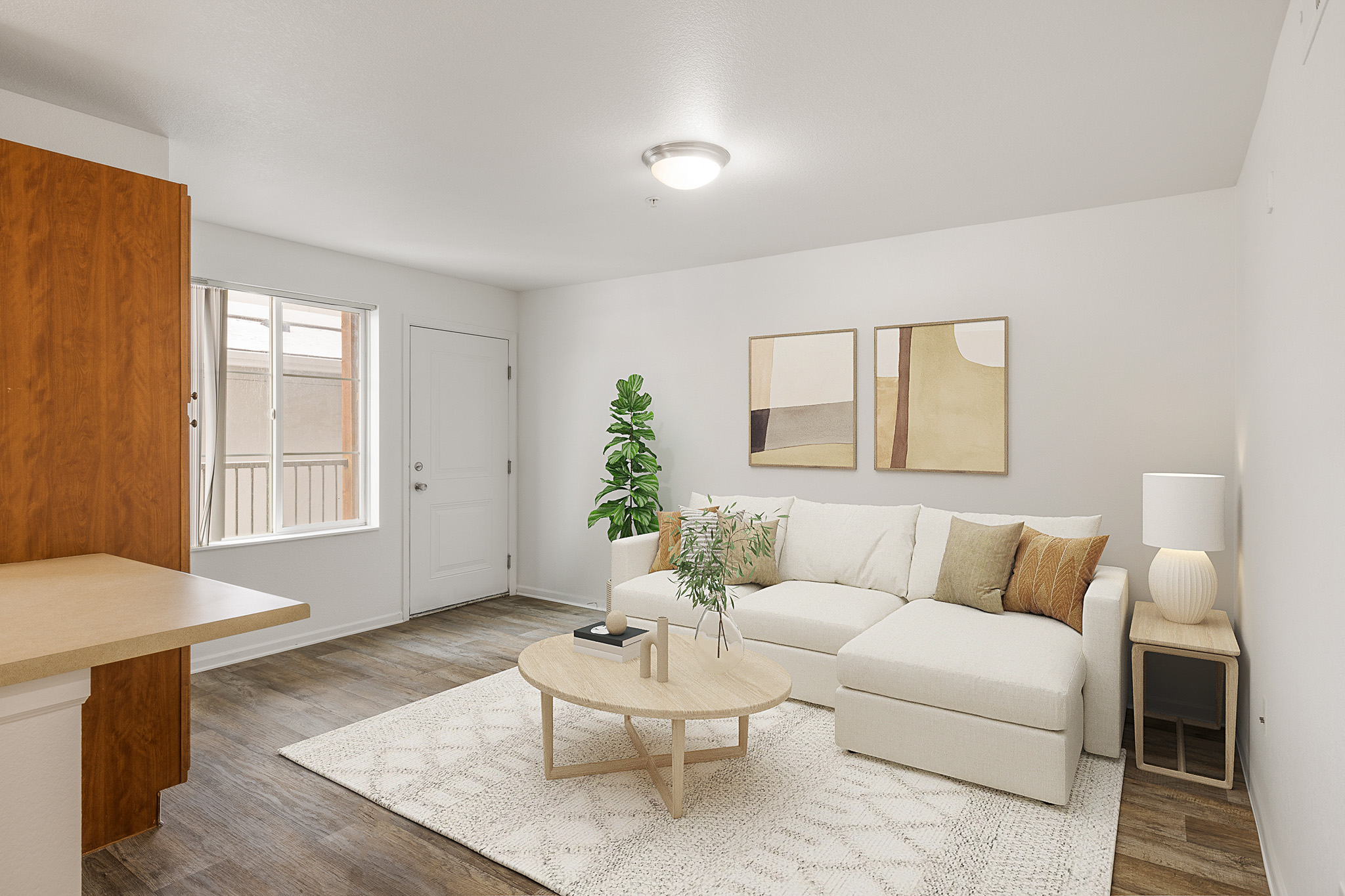 A living room with a white couch, a wooden table, and a potted plant.