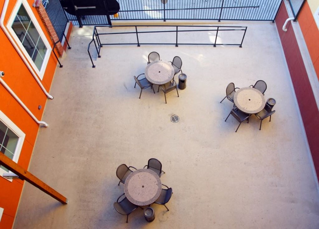 Four round tables are arranged in a square on a patio.