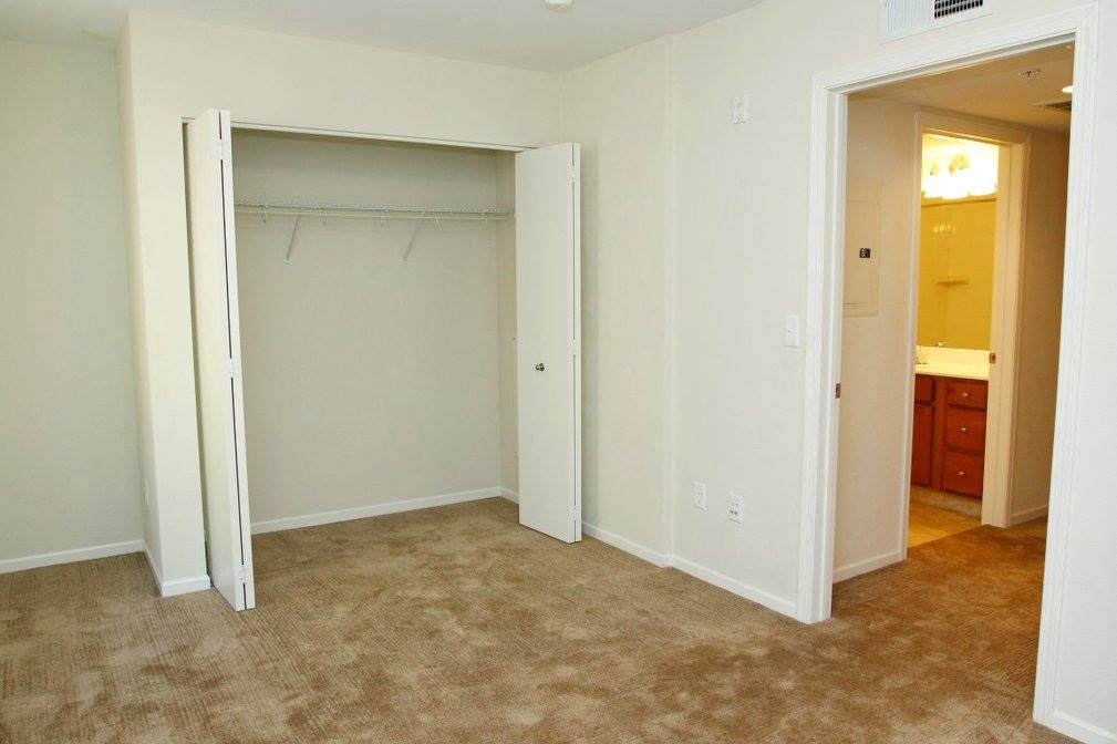 A room with a carpeted floor and a white wall with a doorway leading to another room.