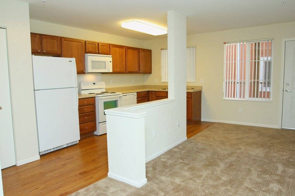 A kitchen with white appliances and wooden cabinets.