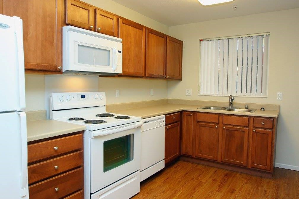 A kitchen with white appliances and wooden cabinets.