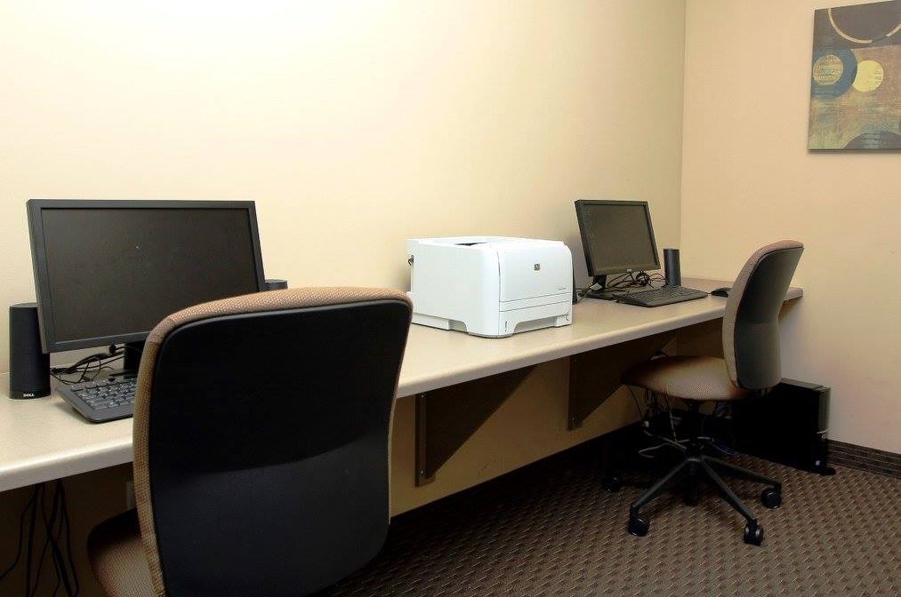 A black monitor is on a desk with a keyboard and a printer.