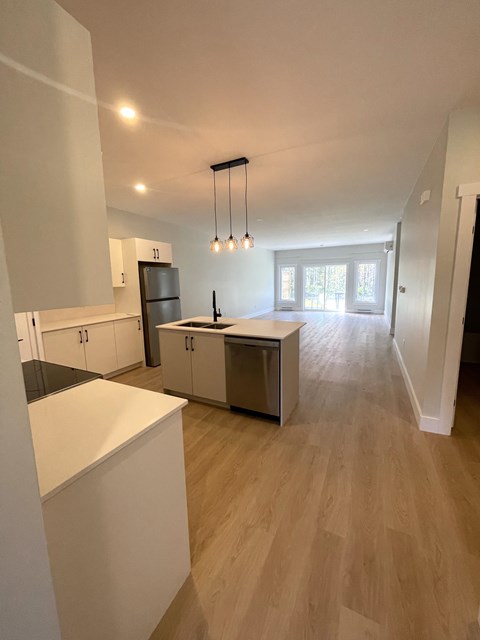 A kitchen with white cabinets and a wooden floor.