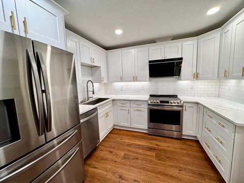 A kitchen with white cabinets and a stainless steel refrigerator.
