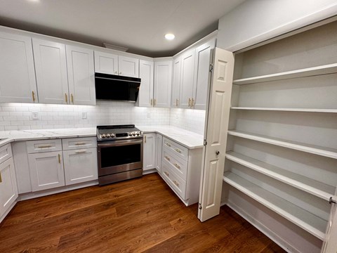 A kitchen with white cabinets and a wooden floor.