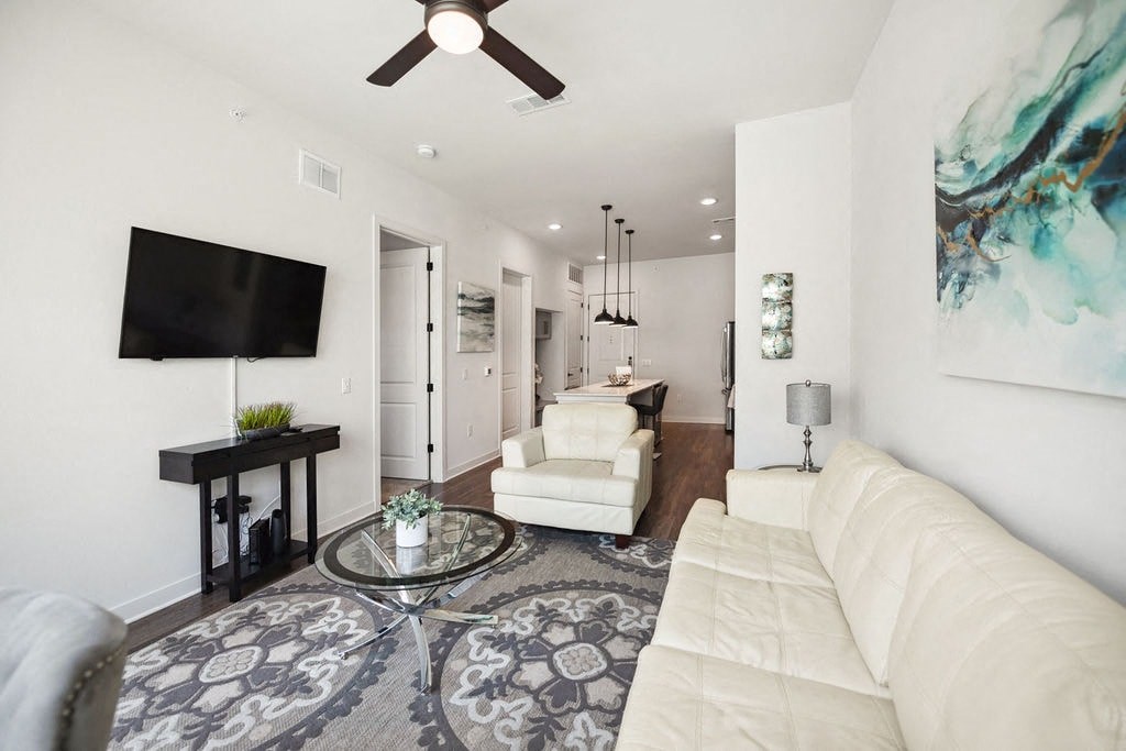 A living room with a white couch and a glass coffee table.