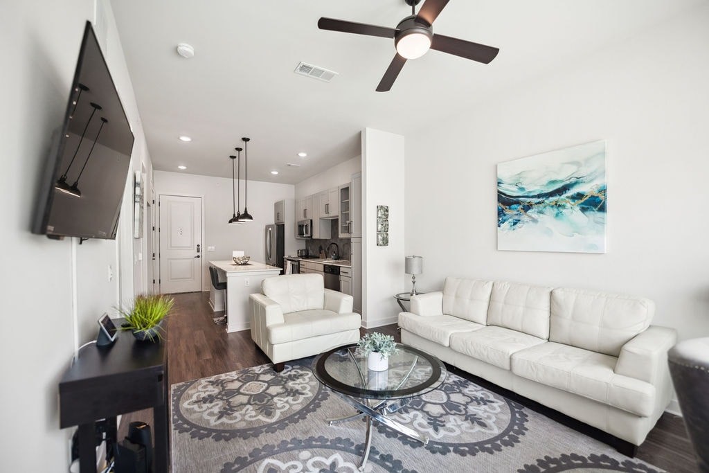 A modern living room with a white couch and a ceiling fan.