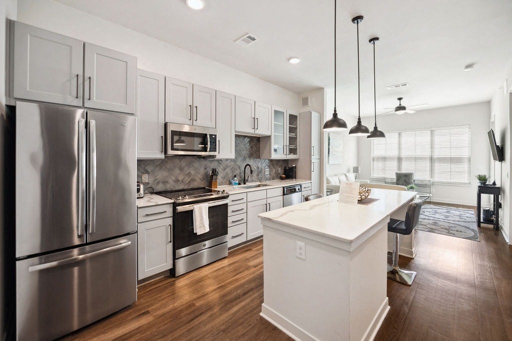 A modern kitchen with a white island and stainless steel appliances.