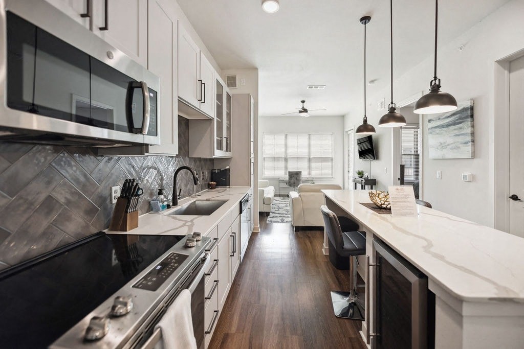 A modern kitchen with a black stove top oven and white cabinets.